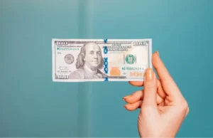 woman-holding-hundred-dollar-bill-teal-background How Long Until I Actually See Money From My Car Accident Claim?