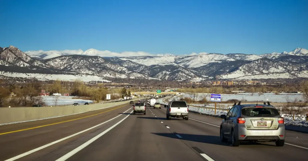 Freeway traffic heading toward snow-capped mountains